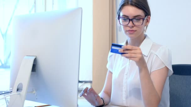 Молодая женщина в офисе делает покупки онлайн с помощью кредитной карты — стоковое видео