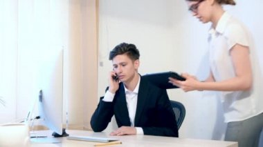 Sekreter erkek patronuna belgeler getiriyor. Bir adam bilgileri denetler