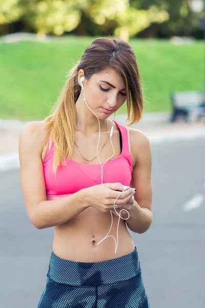 Young female runner turns on the music before the run