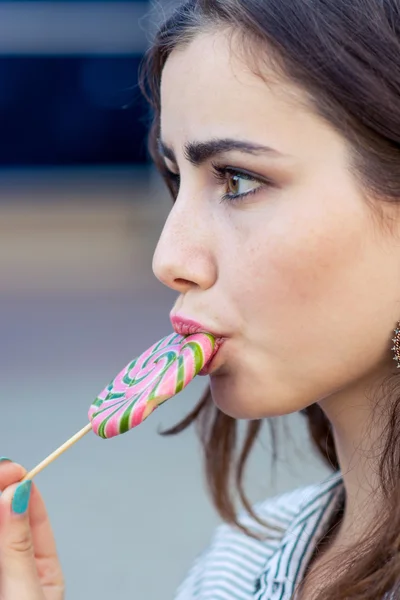 Chica sosteniendo una piruleta en la calle comiendo dulces — Foto de Stock