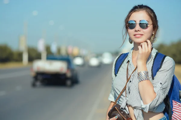 Молодая женщина-путешественница остается рядом с дорогой или шоссе — стоковое фото