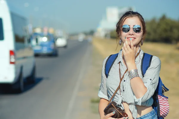 Giovane viaggiatore femminile rimane vicino alla strada o autostrada Foto Stock Royalty Free