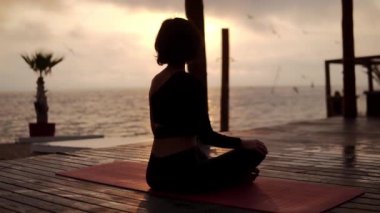 Yogi kızı yazın gün batımında nilüfer çiçeğinin önünde oturuyor, sağlıklı yaşam tarzı, hareket konsepti, meditasyon konsepti.