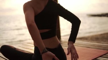 Yoga yapan, omurga ve elleri esneten bir kadın rıhtımda mindere oturuyor. Nadir görülen bir manzarayla el ele tutuşuyor.