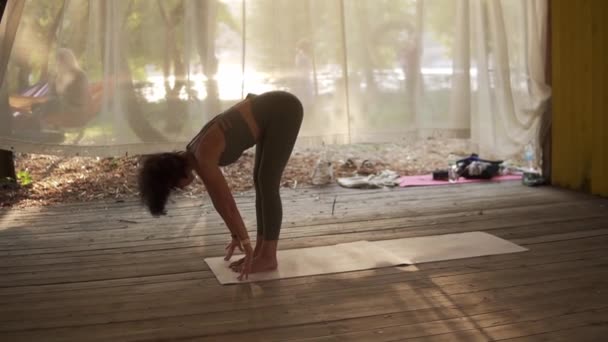 Jovem está fazendo ioga em cabana de madeira cheia de luz, a menina executa stands de ioga e elementos — Vídeo de Stock
