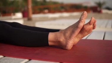 Sahilde yoga yapan atletik bir kadın yoga yapıyor.