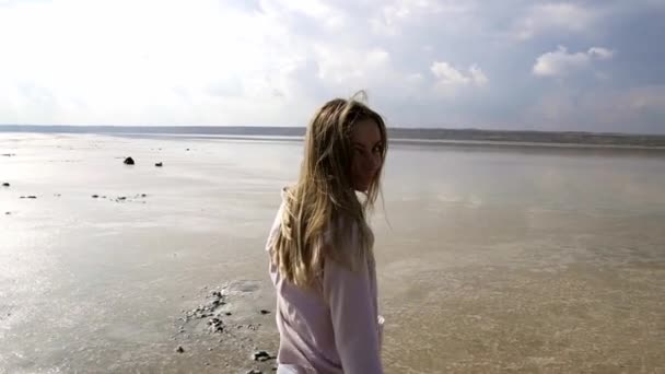Vreugdevolle vrouw in casual loopt op zand ondiep van het meer in de zomer — Stockvideo