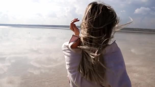 Ritratto di una ragazza sorridente che passeggia lungo la riva del lago, guardando pensierosamente sulla macchina fotografica — Video Stock