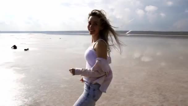 Prachtig meisje aan het meer aan de oever, lopend en lopend op de oever, plezier makend — Stockvideo