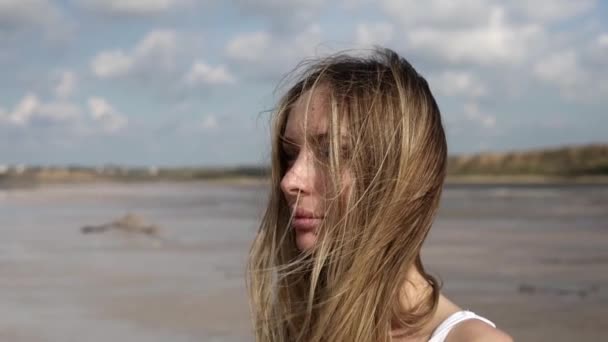 Portret van een langharige attente vrouw met meer op de achtergrond — Stockvideo