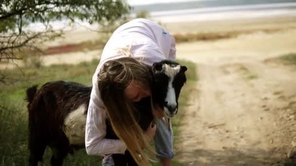 Жінка погладжує козла на відкритому повітрі, пестить його обома руками — стокове відео