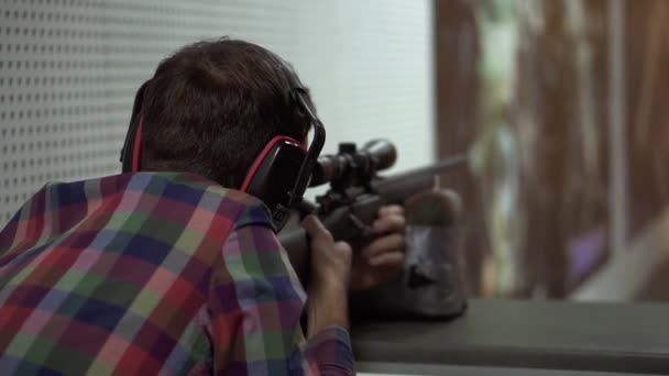 Close-up de um homem atirando uso rifle no alcance de tiro em fones de ouvido — Vídeo de Stock