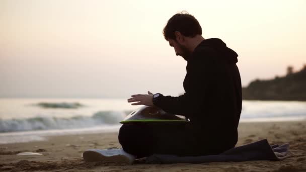 L'uomo che gioca appeso seduto sulla spiaggia di fronte al mare da solo — Video Stock