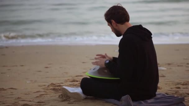 De man in zwart casual spelen hangen op het strand in de voorkant van de zee alleen in de herfst — Stockvideo