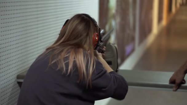 Woman with pneumatic rifle in hands at shooting range with target, excited and surprised by shot — Stock Video