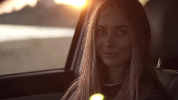Beautiful woman lookingto the camera from the car then go out from the car seat to the seashore — Stock Video