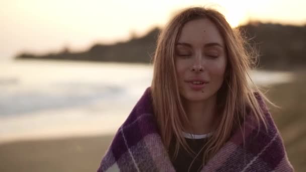 Retrato de uma menina envolta em um cobertor na praia no outono — Vídeo de Stock