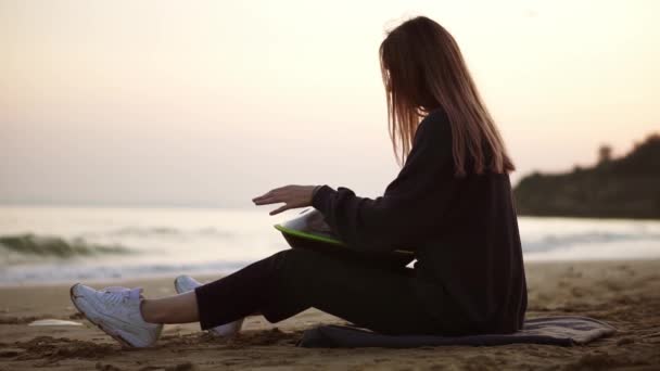 La fille qui joue accrocher assis sur la plage en face de la mer seul — Video