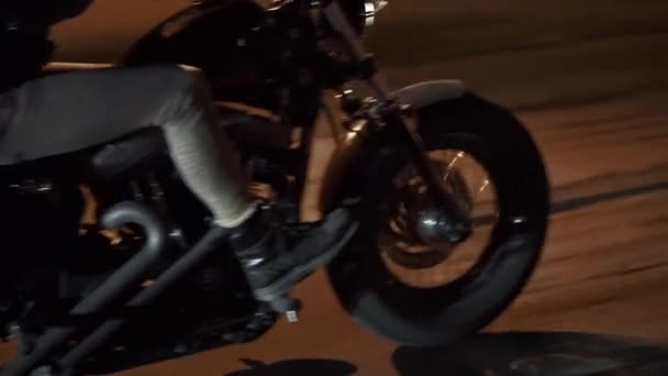 Gece şehir caddesinde motosikletini sürat yapan, tekerlekleri yakın vahşi bir adamın yan görüntüsü. — Stok video