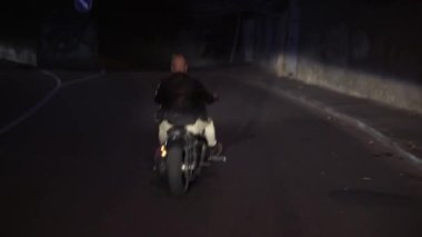Motosiklet süren bir adamın nadir görüntüsü asfalta yapışmış, geceleri kıvılcımlar uçuşuyor.