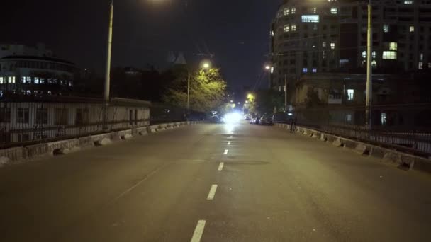Всадник, делающий трюки, едет по городу, стоя на сидении в ночном городе — стоковое видео