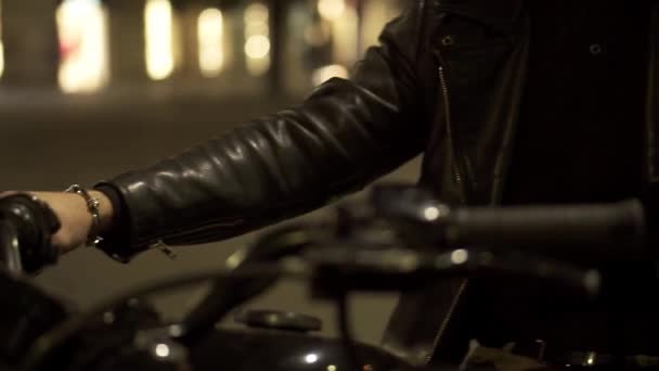 Крупный план красивого всадника, сидящего в кожаной куртке на мотоцикле на городской ночной улице — стоковое видео