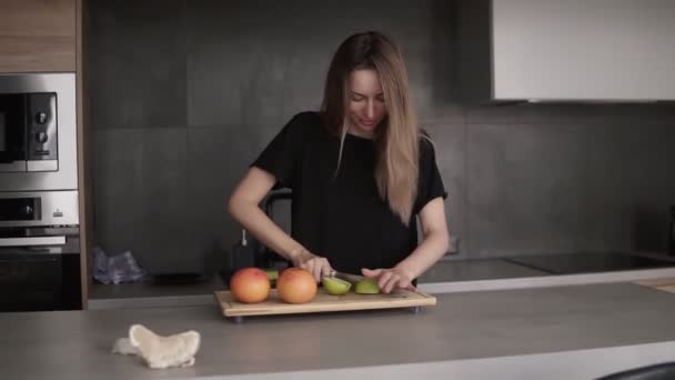Portret młodej kobiety krojącej i czystego zielonego jabłka na desce do krojenia — Wideo stockowe