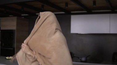 Mutfakta neşeli bir adam dans ediyor ve ekoseyle dalga geçiyor.