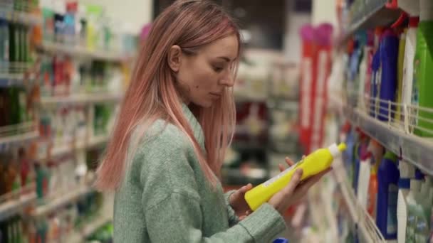 Frau liest Etikett von Haushaltswaren im Supermarkt — Stockvideo