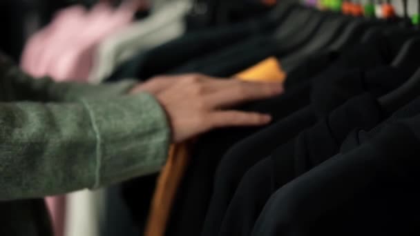 Donna irriconoscibile che sceglie i vestiti dal rack nel negozio di abbigliamento — Video Stock