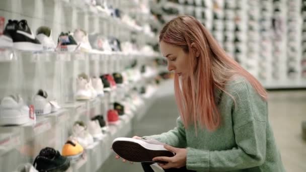 Compras na loja de sapatos, a mulher está escolhendo tênis — Vídeo de Stock