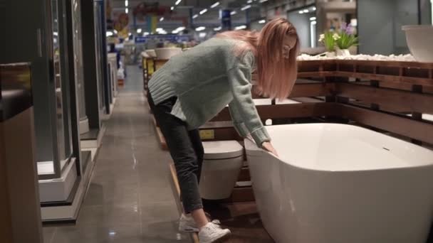 Жінка вибирає і торкається нової ванни в магазині дизайну інтер'єру — стокове відео