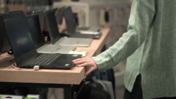 Frau sucht sich Laptop im Gerätehaus aus — Stockvideo