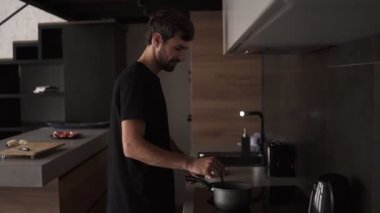 Ev mutfağında yemek pişiren olumlu bir adam.