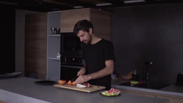 Porträtt av en man som skär grapefrukt på hackbrädan och roliga danser — Stockvideo