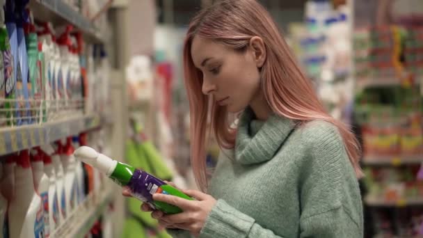 Mulher comprando produtos domésticos no supermercado, lê rótulo — Vídeo de Stock