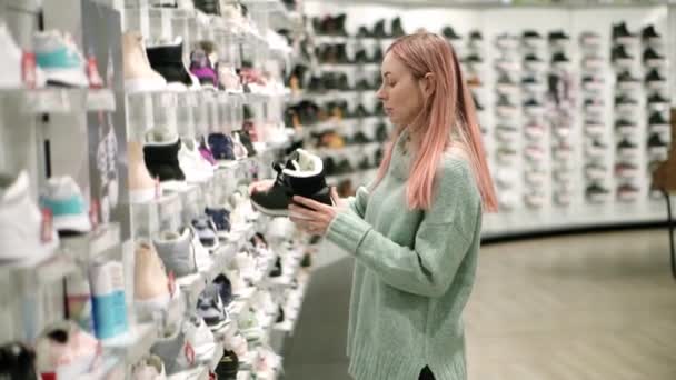 Einkaufen im Schuhgeschäft, Frau wählt Winterstiefel — Stockvideo
