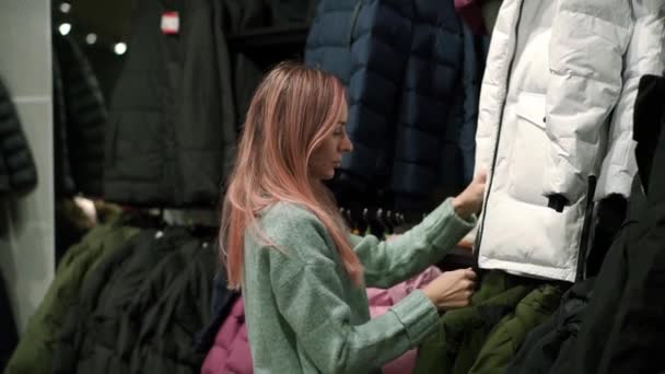 Femme prend une nouvelle veste en duvet d'un rack pour l'adapter — Video