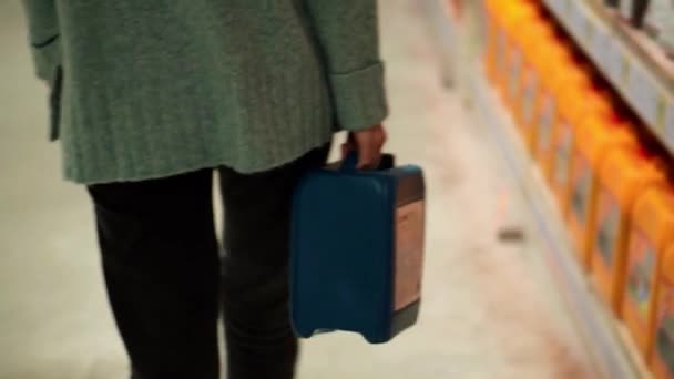 Une femme marchant par la quincaillerie avec une boîte en plastique dans les mains, vue rare — Video