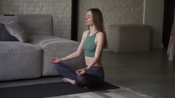 Vrouw in sportkleding die yoga oefeningen doet zittend op de vloer in lotushouding yoga beoefenend — Stockvideo
