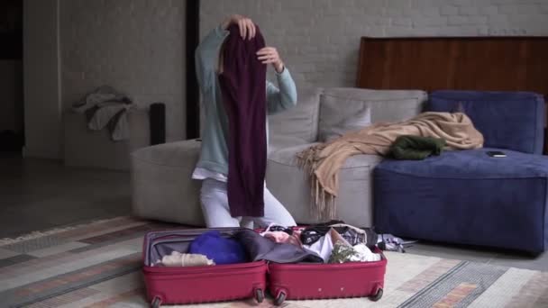 Retrato de uma mulher em um quarto de hotel decifrar roupas de uma mala — Vídeo de Stock