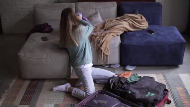 Μια γυναίκα στο σαλόνι βάζει πράγματα σε μια βαλίτσα, αργοκίνητε. — Αρχείο Βίντεο