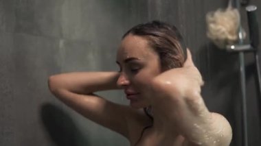 Duşta saçını yıkayan genç sarışın kadın.