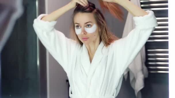 Blondýny vlasy žena česá její vlasy v koupelně u zrcadla — Stock video
