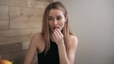 İnce bir kadın masadan takviye hapı alıyor ve bir bardak su içiyor.