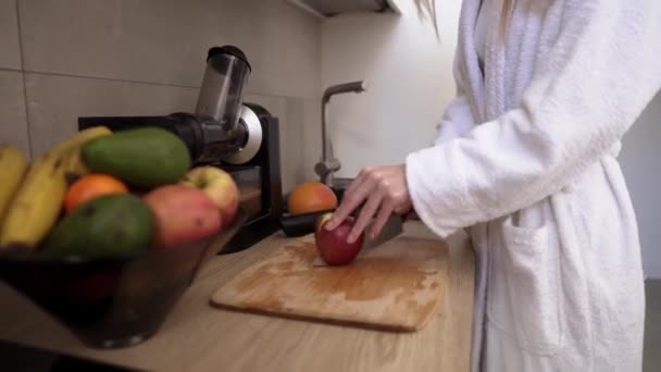 Donna che taglia mela con un coltello su un tagliere di legno per fare succo — Video Stock
