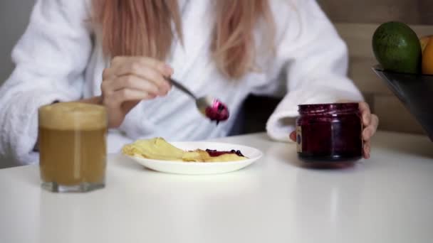 Женщина завтракает блинчиками с джемом и свежим яблочным соком дома — стоковое видео