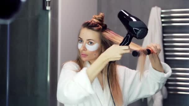 Kobieta z przepaskami na oczy suszenie włosów z suszarką do włosów i szczotką — Wideo stockowe