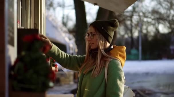 Женщина выбирает товары в уличном киоске на зимней прогулке, подумайте о порядке — стоковое видео