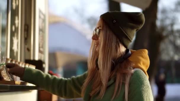 女人想吃姜饼，冬天散步时在街上的咖啡店里喝咖啡 — 图库视频影像